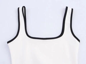 Detailed close-up of white tank top with black contrast piping and fine needlework