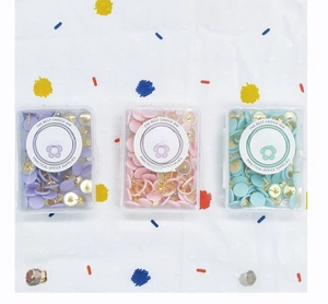 Vue de dessus de punaises colorées macaron dans trois boîtes de rangement en plastique