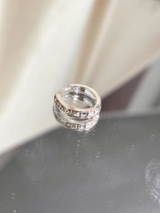 Macro shot of silver hoop earrings with square zircon stones on a mirror surface