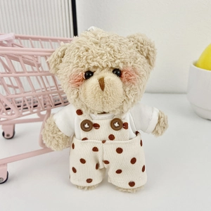 Dettaglio dell'orso di peluche beige in salopette a pois con morbida texture
