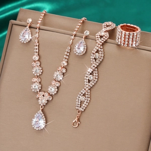 Rose gold bridal jewelry set with teardrop rhinestones on green satin fabric backdrop