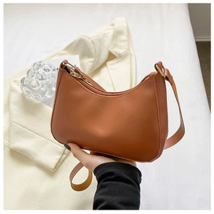 Detalle de un bolso de hombro medialuna marrón de cuero sintético con cremallera