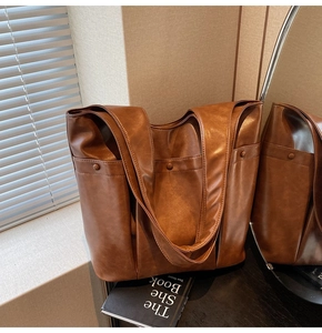 Detail of soft brown leather tote bag with double straps in a minimalist lifestyle setting