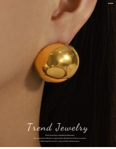 Close-up of model wearing large hollow gold-plated dome earrings with polished mirror finish