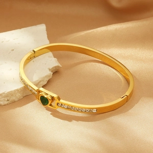 Detail of gold-plated hinged bangle with green heart-shaped stone and zircon inlay