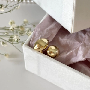 Close-up of minimalist gold geometric stud earrings nestled in a pink gift wrap box