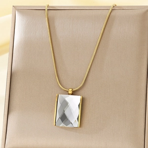 Detail of gold snake chain necklace with transparent square glass pendant on jewelry box