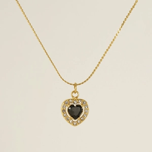 Detail of gold heart pendant necklace featuring a black gem center and clear zircon border