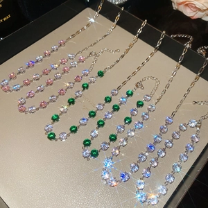 Macro shot of silver necklaces set with sparkling pink, green, and clear round zircons