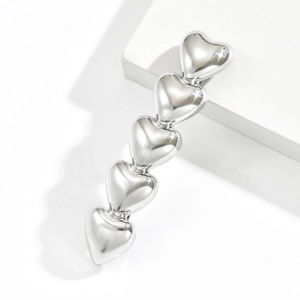 Minimalist silver metal hair clip with five hollow heart shapes on a white stone base