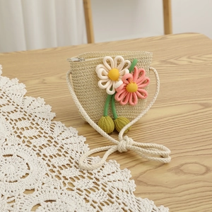 Close-up of handmade straw crossbody bag with crochet flowers and a cotton rope strap