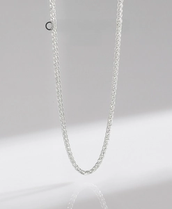 Macro shot of silver S925 wheat chain necklace with bright metallic luster and weave texture
