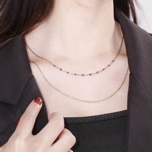 Détail d'un collier doré multicouche avec perles mauves sur le cou du mannequin