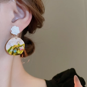 Close-up of vintage butterfly and floral drop earring with colorful enamel patterns