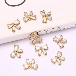 Macro detail of golden bow-shaped pendants with sparkling cubic zirconia on a white surface