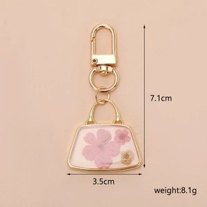 Detailed size view of pink dried flower purse keychain with gold metal hooks and charms