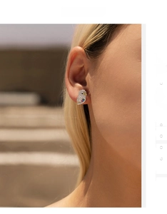 Macro shot of s925 silver owl stud earring with colorful cubic zirconia on ear