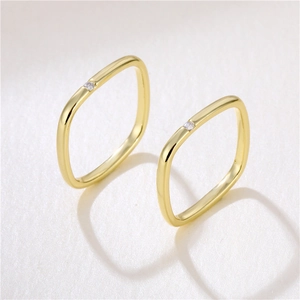 Minimalist square 18K gold ring with a single zircon stone set on a white textured background