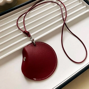Macro shot of red leather circular card holder with white stitching and silver hardware