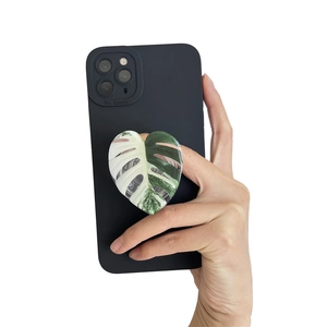 Collapsible heart-shaped phone grip with Monstera leaf design on a black mobile case
