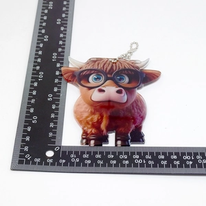 Detailed view of brown cartoon highland cow acrylic keychain with silver bead chain