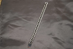 Dettaglio ravvicinato di un bracciale a catena cubana in argento su raso grigio scuro testurizzato