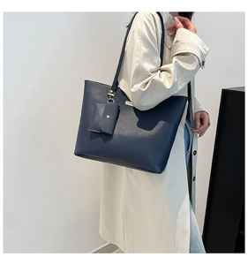 Detail of navy tote bag with lychee texture leather and a small matching pouch accessory