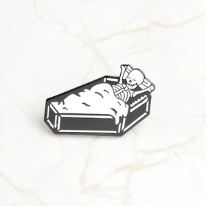 Detail of gothic enamel skull pin in coffin on a luxury marble background