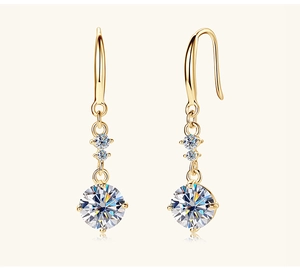 Macro detail of gold hook earrings with three graduated white round stones
