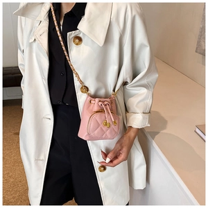 Close-up of pink quilted mini bucket bag with chain strap and flower gold hardware