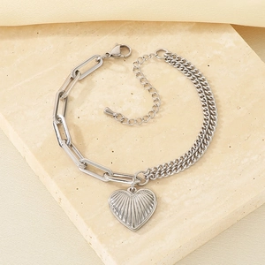 Close-up of silver-toned mixed link chain bracelet with heart-shaped pendant on marble