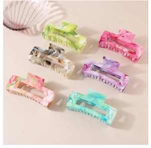 Set of six colorful marble textured rectangle hair claws in a minimalist flat lay arrangement