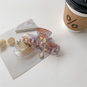 Macro shot of marble textured acetate hair claw clip on a stylish cafe setting background