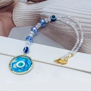 Macro detail of evil eye heart pendant with blue faceted beads and gold lobster clasp