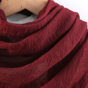 Solid wine red linen scarf with natural crinkle texture hanging on a wooden hanger