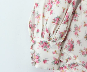 Detailed macro view of floral dress cuffs with elegant ruffles and three fabric buttons