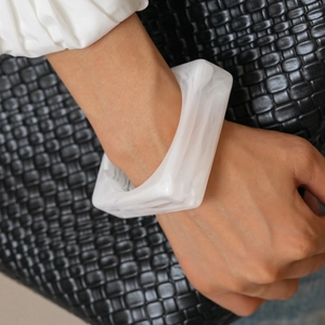 Detailed close-up of white marble pattern resin square bangle on person's wrist