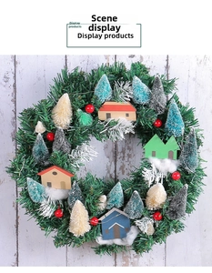 Close-up of a Christmas wreath with miniature houses and snowy pine needles