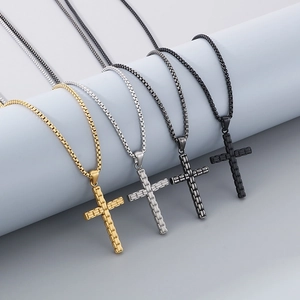 Détail de quatre pendentifs croix à motifs texturés en or, argent, gris et noir