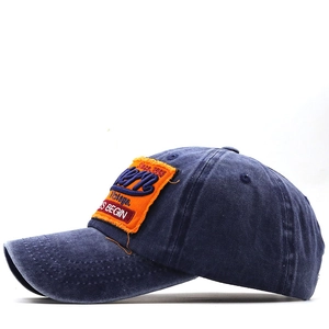 Dettaglio del cappellino da baseball vintage in cotone blu con toppa ricamata arancione