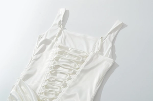 Detail van de witte satijnen jurk met een elegante vetersluiting op de rug en glanzende stof