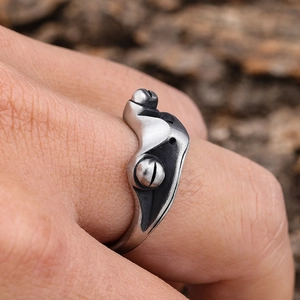 Close-up of retro silver stainless steel frog eye ring on male finger with wood background
