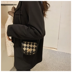 Detail einer Mini-Satteltasche mit schwarz-weißem Karomuster und goldenem Drehverschluss