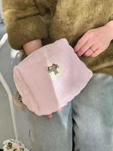 Handheld view of pink quilted fabric cosmetic bag with minimalist cat patch detail