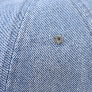 Macro shot of light blue denim fabric featuring precise stitching and embroidered eyelet