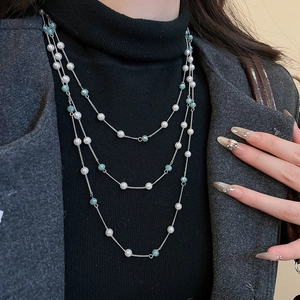 Dettaglio della collana argentata a strati con perle bianche e cristalli turchesi