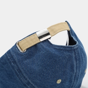 Adjustable canvas strap and metal buckle on the back of a blue denim baseball cap