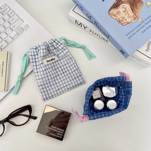Close-up of checkered drawstring storage bags for cosmetics on a minimalist desk setup
