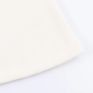 Detailed macro view of cream knitted fabric texture with professional hem finishing
