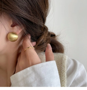 Detail of matte gold geometric spherical stud earrings with textured cross pattern